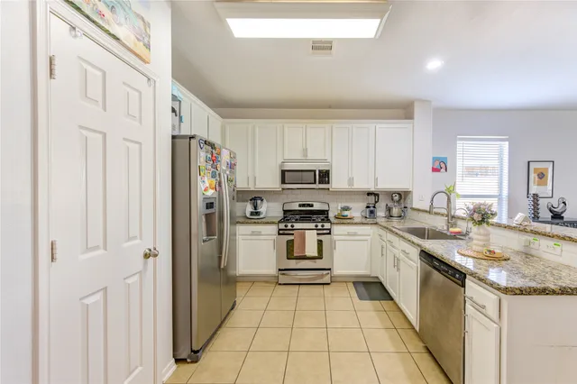 a kitchen with stainless steel appliances granite countertop a stove top oven a sink a counter top space and cabinets