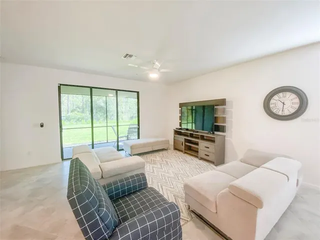a living room with furniture a flat screen tv and a large window