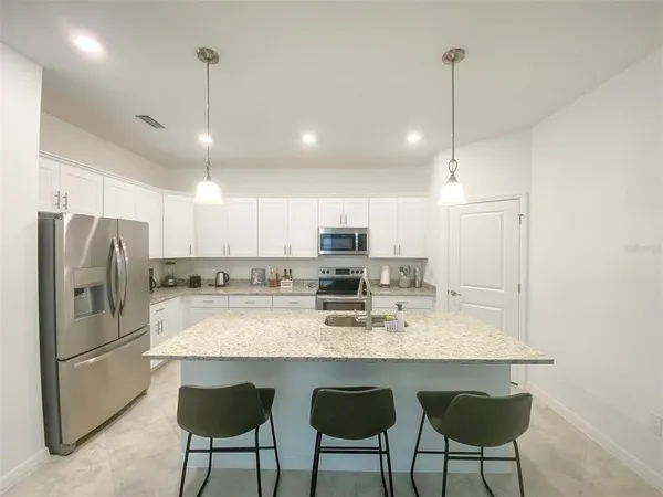 a kitchen with refrigerator a sink and chairs