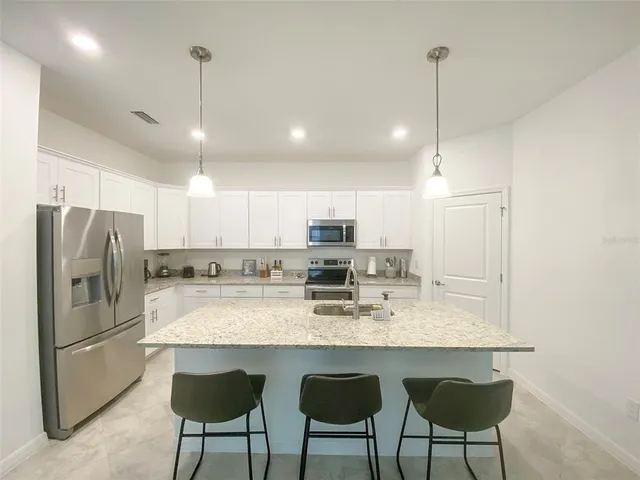 a kitchen with refrigerator a sink and chairs