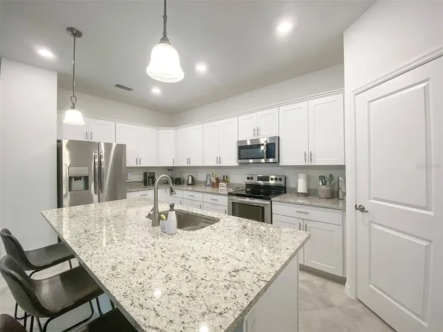 a kitchen with stainless steel appliances granite countertop a sink refrigerator and cabinets