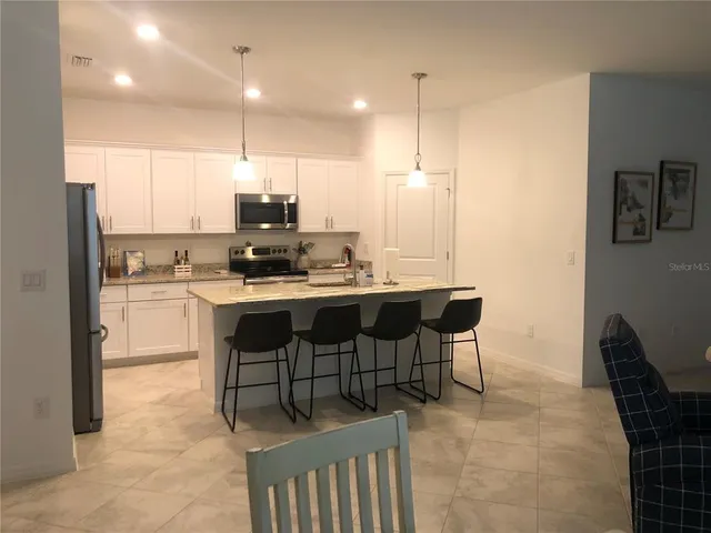 a kitchen with kitchen island a stove a sink a refrigerator and a dining table