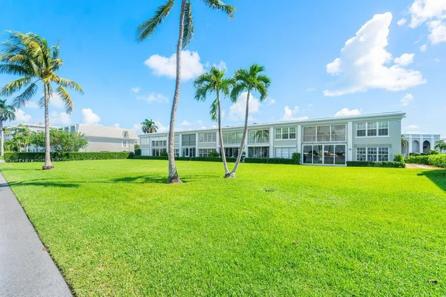 a view of a house with a big yard and palm trees
