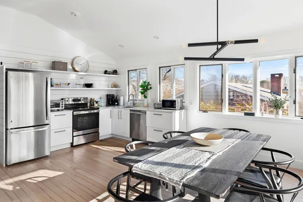 a kitchen with stainless steel appliances granite countertop a stove a refrigerator a dining table and chairs with wooden floor