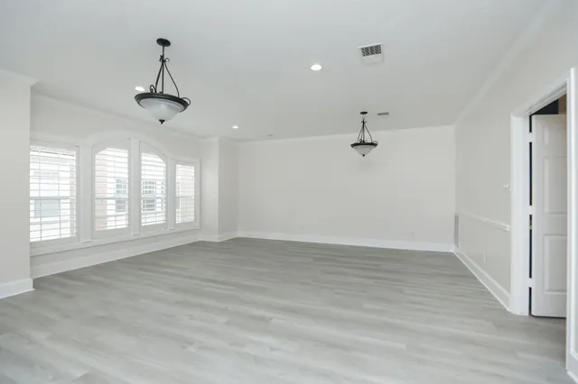 an empty room with windows fireplace and wooden floor