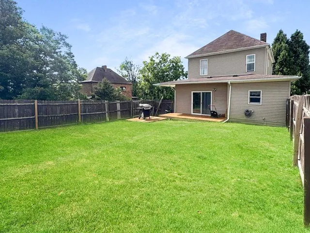 a view of a house with a yard and a large tree
