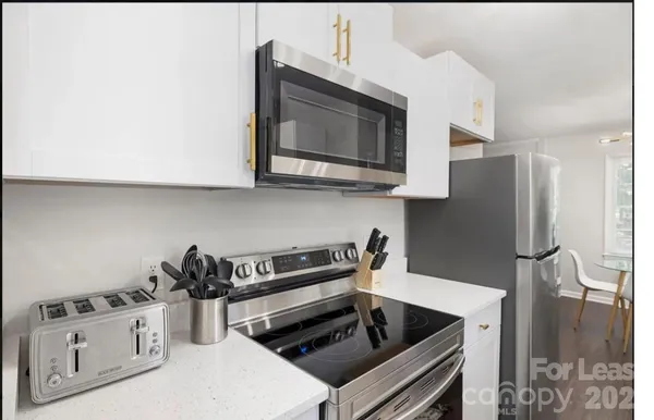 a kitchen with stainless steel appliances granite countertop white cabinets and a stove top oven