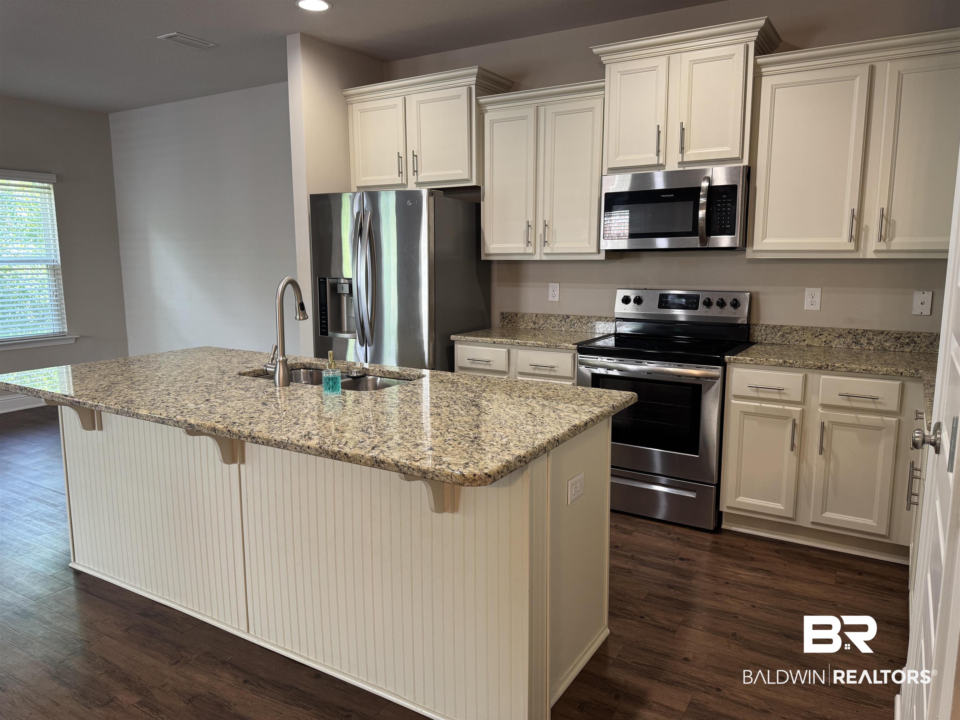 6811 Spaniel Drive, Unit C Daphne, AL 36527 - Photo 2 of 33 Kitchen with appliances with stainless steel finishes, a sink, white cabinets, dark wood-type flooring, and a center island with sink