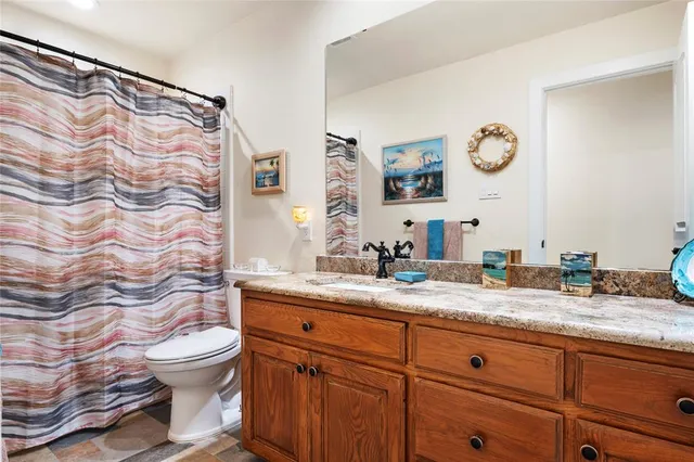a bathroom with a granite countertop sink mirror vanity and toilet