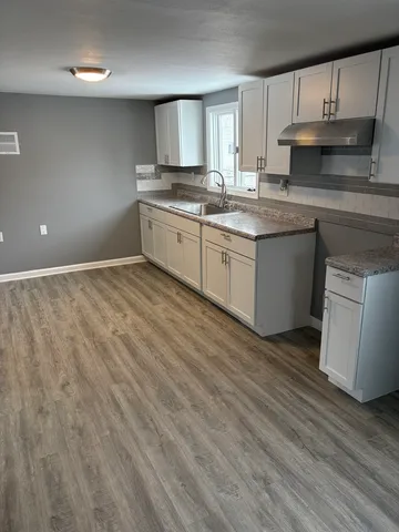 a kitchen with stainless steel appliances granite countertop a sink a stove a refrigerator with grey cabinets and wooden floor