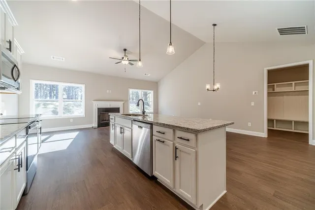 a kitchen with stainless steel appliances granite countertop a refrigerator a sink dishwasher a stove and white countertops with wooden floor