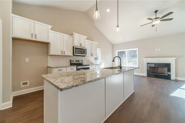 a kitchen with stainless steel appliances granite countertop a stove a sink dishwasher a refrigerator and a microwave oven with wooden floor