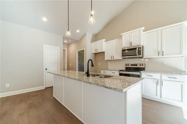 a kitchen with kitchen island granite countertop a sink stainless steel appliances and white cabinets