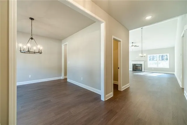 a view of empty room with wooden floor and kitchen view