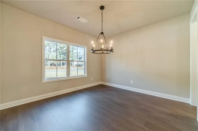an empty room with wooden floor chandelier and windows