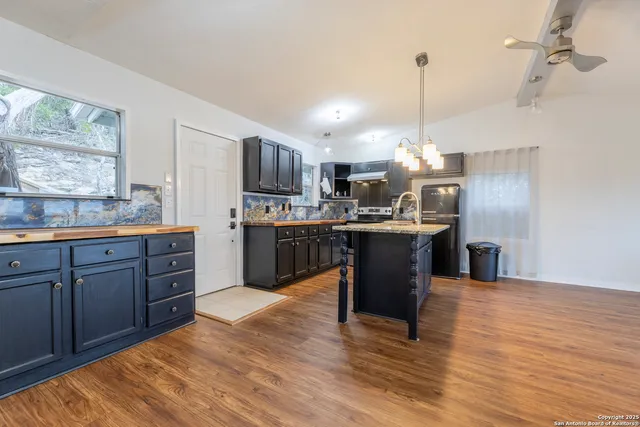 a kitchen with kitchen island granite countertop a sink a counter top space stainless steel appliances and cabinets