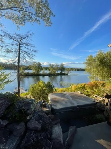 a view of a lake with lawn chairs and large trees