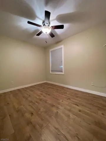 a view of an empty room with chandelier fan and wooden floor
