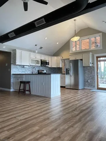 a kitchen with stainless steel appliances kitchen island granite countertop a stove and a wooden floors