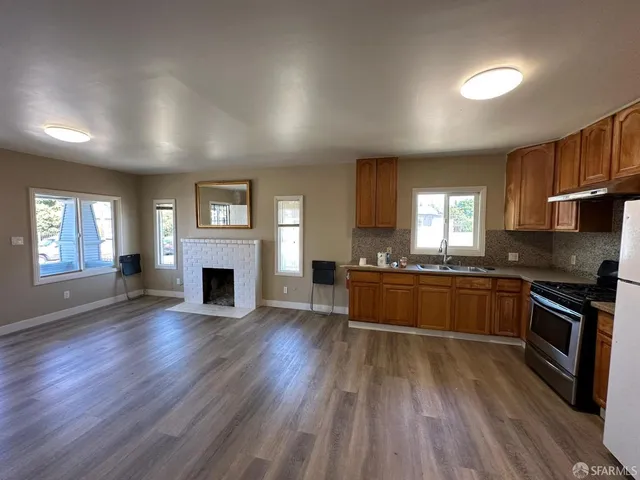 an empty room with fireplace wooden floor and windows