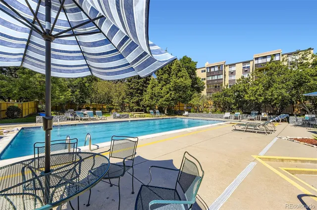 a view of a swimming pool with lawn chairs under an umbrella