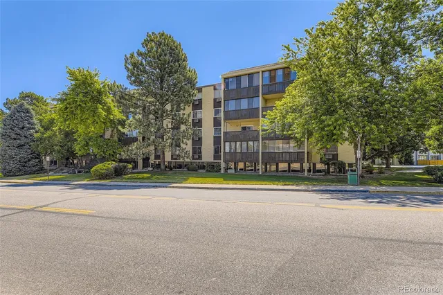 a multi story building with trees in front of it