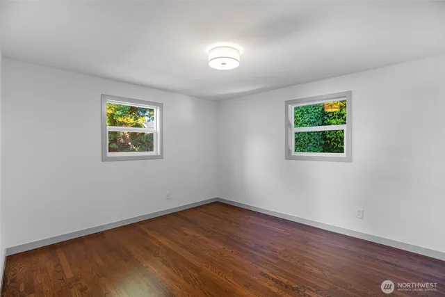 a view of empty room with wooden floor and window