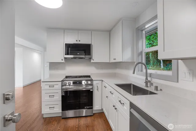 a kitchen with cabinets stainless steel appliances a sink and a window