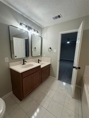 a bathroom with a double vanity sink mirror and bathtub