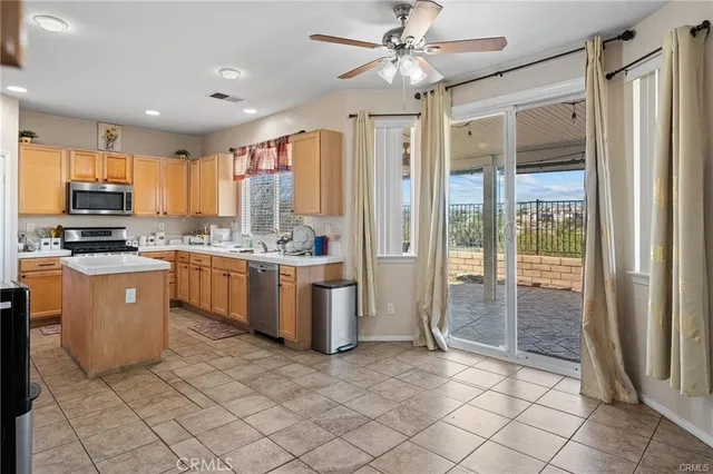 a kitchen with stainless steel appliances granite countertop a refrigerator a sink a stove top oven a counter space and a view of living room