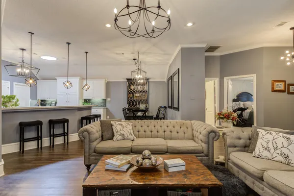 a living room with furniture kitchen view and a chandelier