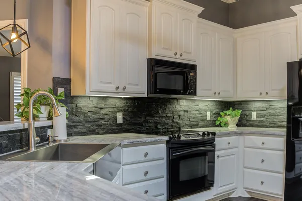 a kitchen with granite countertop white cabinets stainless steel appliances and a sink