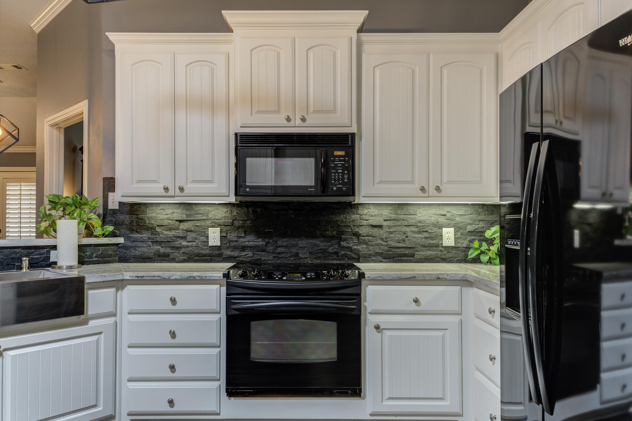6005 83rd Street Lubbock, TX 79424 - Photo 23 of 47 a kitchen with white cabinets and black appliances