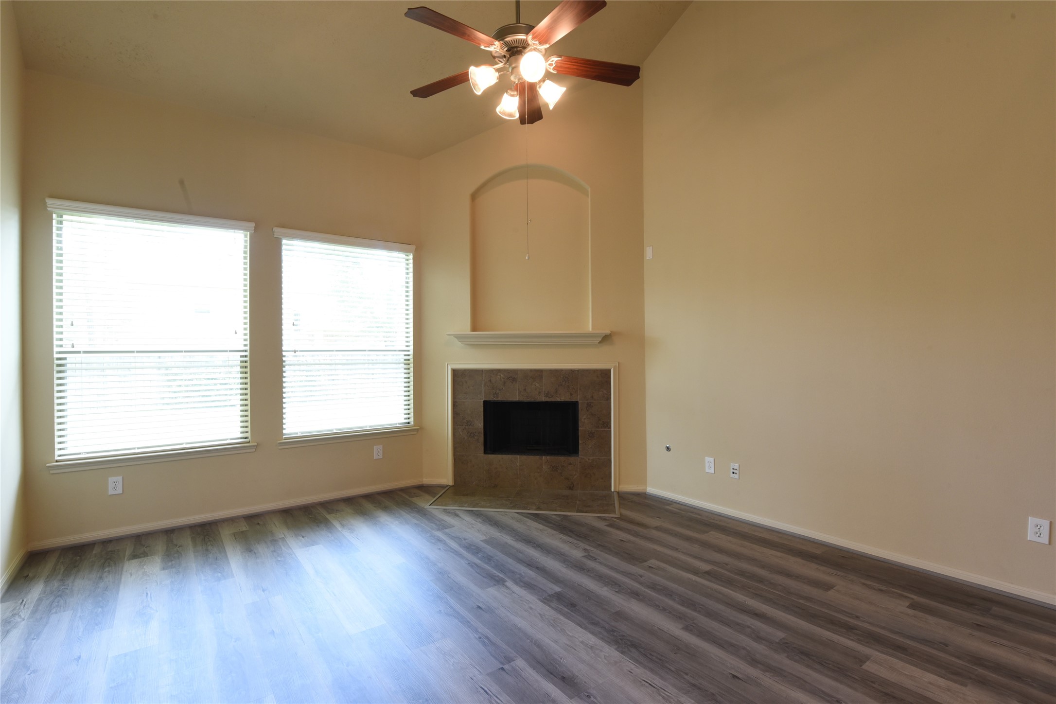 118 East Lasting Spring Circle Spring, TX 77389 - Photo 19 of 46 Bright living room with high ceilings, elegant ceiling fan, and cozy fireplace, featuring large windows and stylish Luxurious Vinyl Laminate flooring.