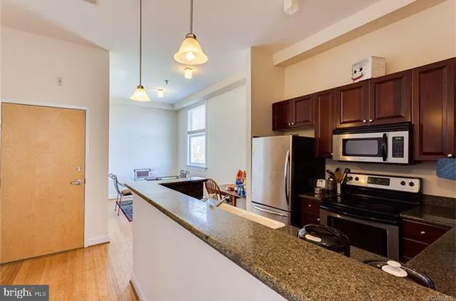 a kitchen with stainless steel appliances granite countertop a refrigerator a stove and a sink