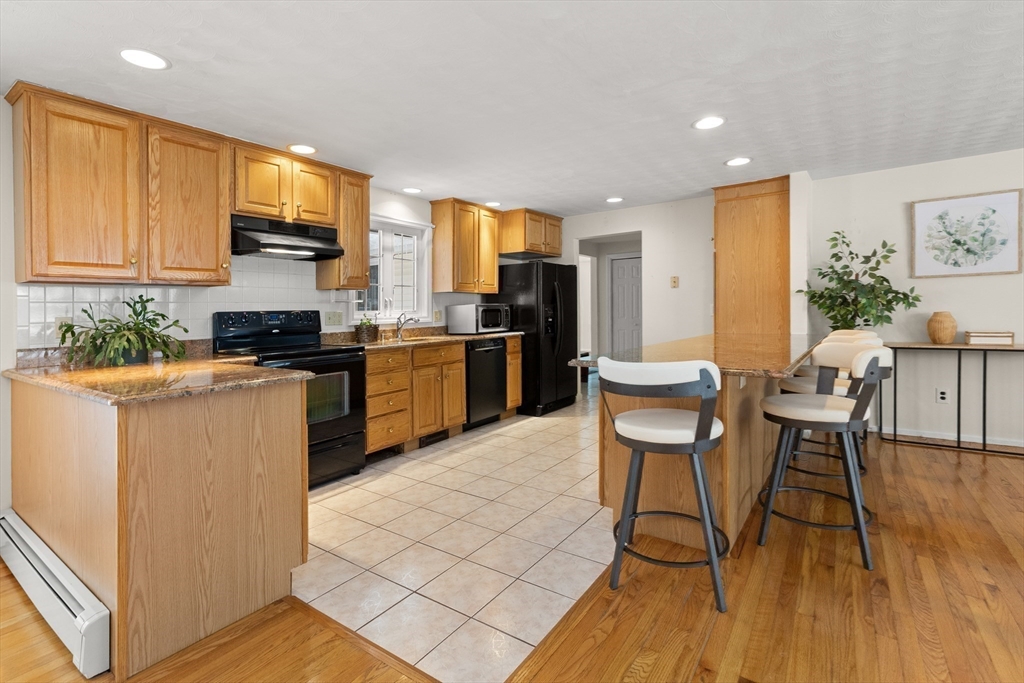12 Tulane Road Danvers, MA 01923 - Photo 17 of 25 a kitchen with stainless steel appliances a stove a sink a microwave a dining table and chairs