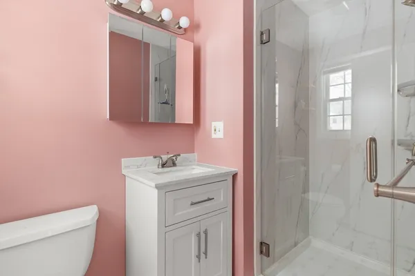 a bathroom with a sink a toilet a mirror and shower