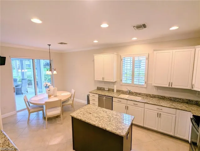 a kitchen with a stove a sink dishwasher a dining table and chairs with wooden floor