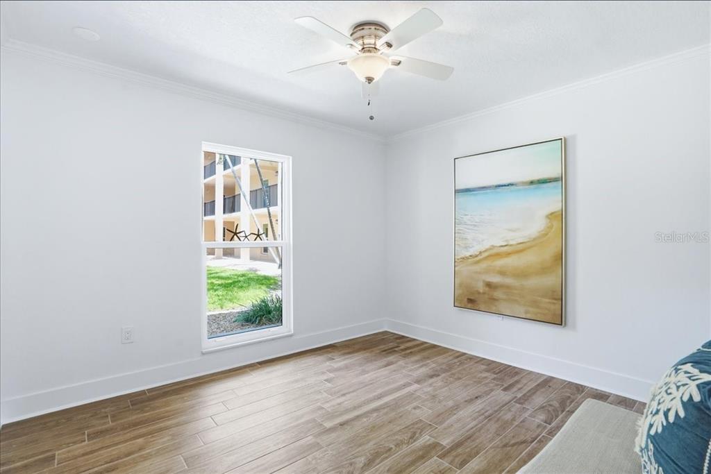 8911 Blind Pass Road, Unit 118 St. Pete Beach, FL 33706 - Photo 31 of 34 an empty room with wooden floor ceiling fan and windows
