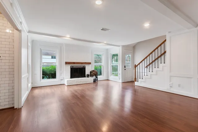 a view of an empty room with wooden floor fireplace and a window