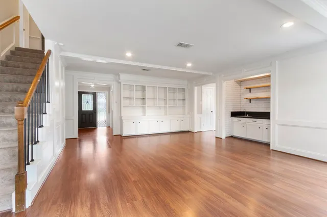a view of empty room with wooden floor and kitchen