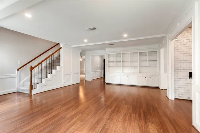 a view of an empty room with wooden floor and windows