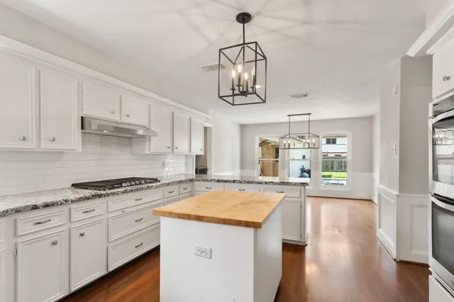 a kitchen with stainless steel appliances granite countertop a sink a stove and white cabinets