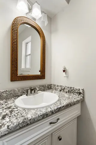 a bathroom with a granite countertop sink a mirror and vanity