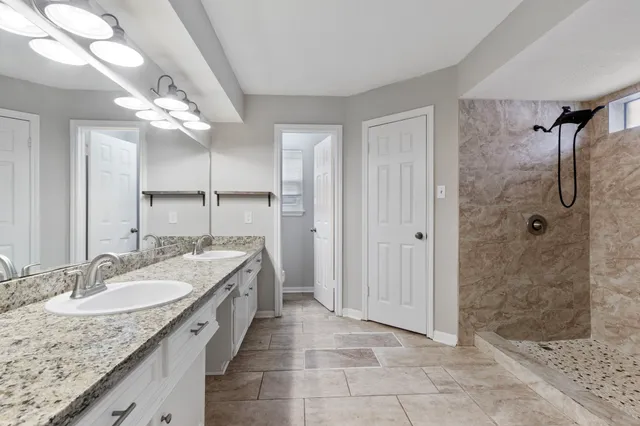 a spacious bathroom with a granite countertop sink a mirror and shower