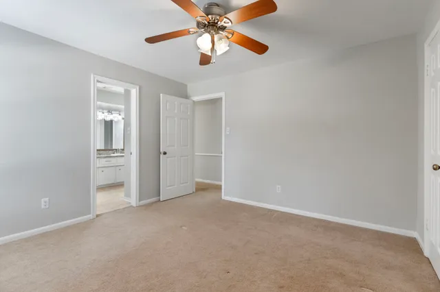 a view of an empty room and chandelier fan