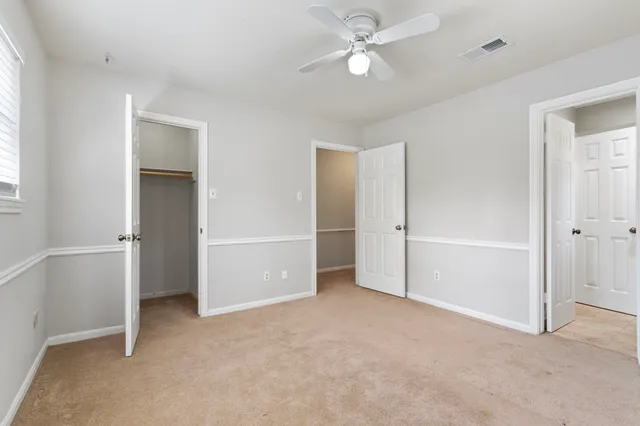 an empty room with closet and a ceiling fan