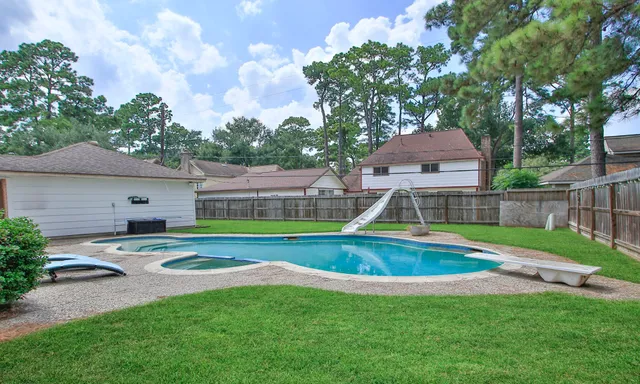 a view of backyard with swimming pool and seating space