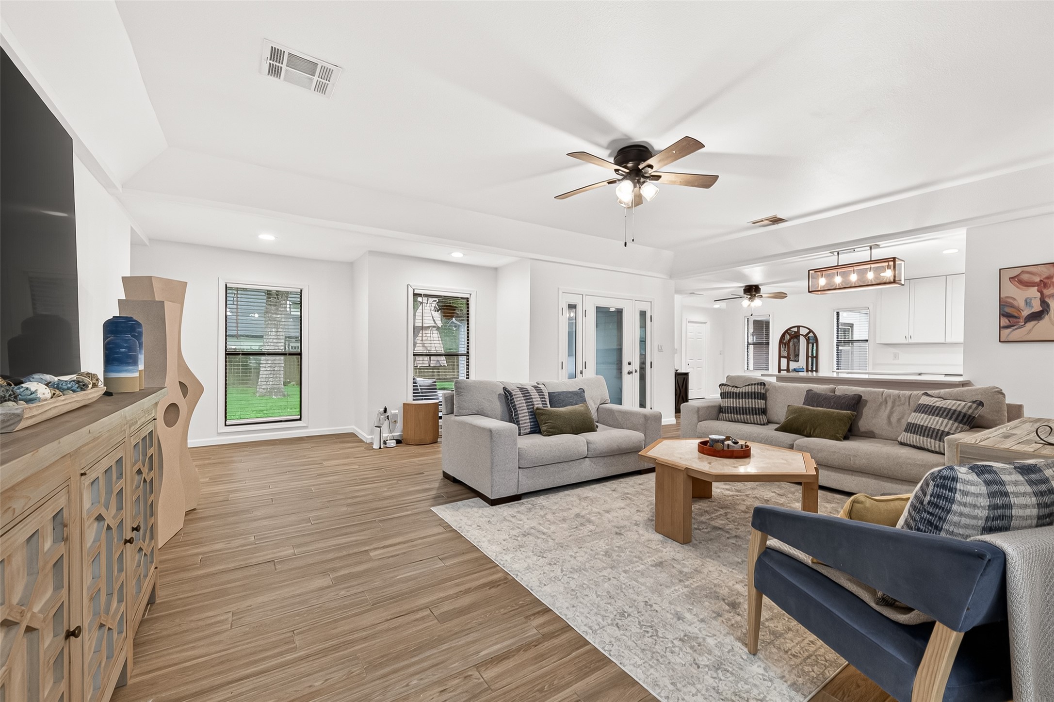 548 Brandon Road Conroe, TX 77302 - Photo 3 of 37 Bright and inviting open concept living room featuring wood like tile flooring, abundant windows for natural light and furnished in modern tones that create a warm and welcoming atmosphere.