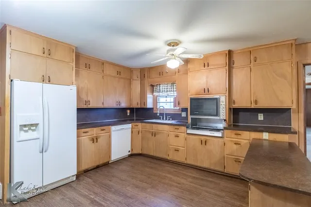 a kitchen with granite countertop a sink appliances cabinets and counter space